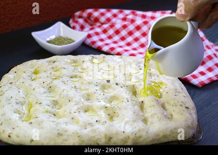 Pouring Olive Oil on Focaccia Bread Dough Surface before Baking Stock Photo