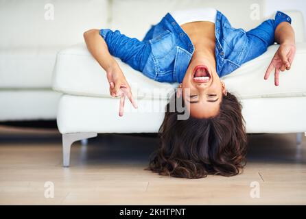 Woman, sofa and peace hands upside down for funny relax portrait in living room at home. Happy, comic girl and excited, laughing and relaxing on sofa Stock Photo