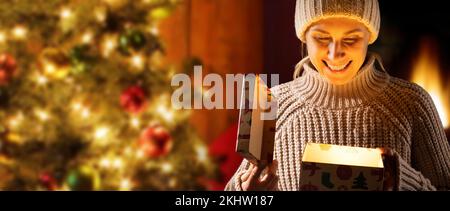 happy woman opening christmas present box. magic gift with light inside. banner with copy space Stock Photo