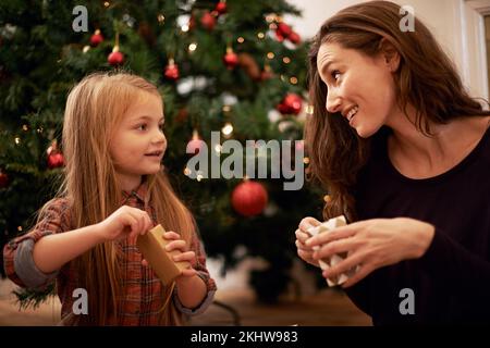 Christmas gifts, family and mother with girl, having fun or bonding in home. Love, care and happy mom with child opening presents on xmas day, smile Stock Photo