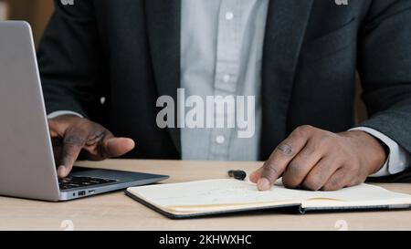 Close-up male hands writing in notebook with pen make notes information financial analysis startup project management idea sitting at desk in office Stock Photo