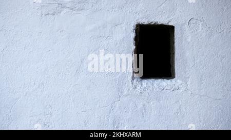 Background with white plaster wall and a small window Stock Photo