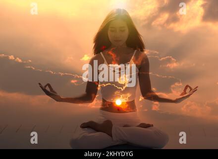 Young spiritual meditation aura woman with her eyes closed feeling free on nature energy at sunrise. Stock Photo