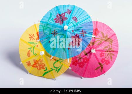 Three decorative paper umbrellas of three different colors against a white background Stock Photo