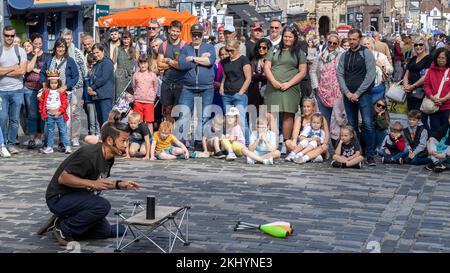 An Edinburgh Fringe street performer entertains an audience of adults and children on Edinburgh's Royal Mile with a mixture of magic and juggling. Stock Photo