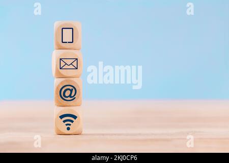 Close up Wooden block cube with communication symbol icon mobile phone, email, address and wifi on table Stock Photo
