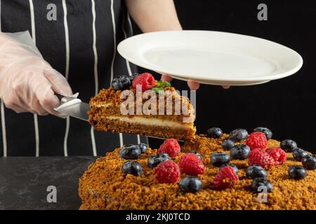 A female chef bakes and eats a piece of homemade carrot cake on a dark background. selective focus Stock Photo