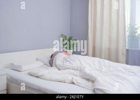 A bearded young man is sleeping in cozy bed. Happy to sleep. Healthy sleep of a man in a fresh white bed. Stock Photo