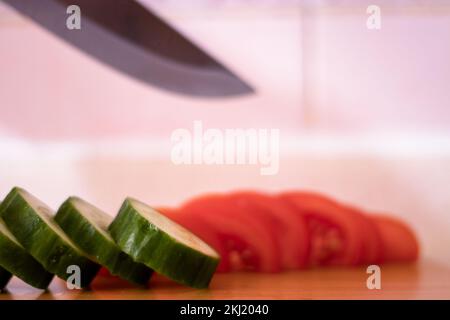 Knife background of freshly cut tomatoes and sliced ​​cucumbers .Selective focus Stock Photo