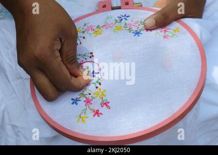 Horana, Kalutara, Sri Lanka -July 30, 2022:Close up view of an asian woman sewing a hand embroidery using a needle and red thread Stock Photo