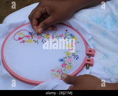 Horana, Kalutara, Sri Lanka -July 30, 2022:Side view of an asian woman sewing a hand embroidery using a needle and red thread Stock Photo