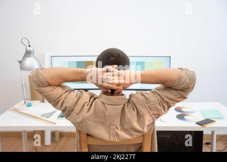 Young Handsome Man Working from Home on Desktop Computer. Creative Designer relaxed in his work set. Stock Photo