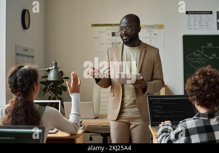 African American teacher using digital tablet while working with children during lesson Stock Photo