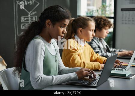 Group of children sitting at desk in a row and working with new software on computers at class Stock Photo