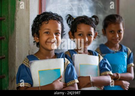 Three School Children's holding books standing at school Stock Photo ...