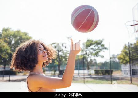 Mixed race young smiling female outdoors and having fun. Stylish cool teen girl gathering at basketball court, playing basketball outdoors Stock Photo