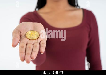 Young black woman showing a bitcoin coin to the camera on a white background. Stock Photo