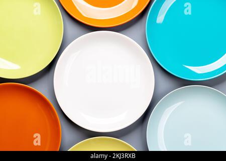 Different clean colorful plates on grey background. Flat lay with copy space Stock Photo