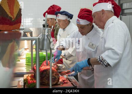 Fussa, Japan. 24th Nov, 2022. U.S. Ambassador to Japan Rahm Emanuel, 2nd right, and U.S. Air Force Lt. Gen. Ricky Rupp, right, Commander of Forces Japan, dressed in chefs uniforms, serve ham and turkey to service members during Thanksgiving at the Samurai Cafe Dining Facility at Yokota Air Base, November 24, 2022 in Fussa, Japan. Credit: TSgt. Christopher Hubenthal/US Air Force/Alamy Live News Stock Photo