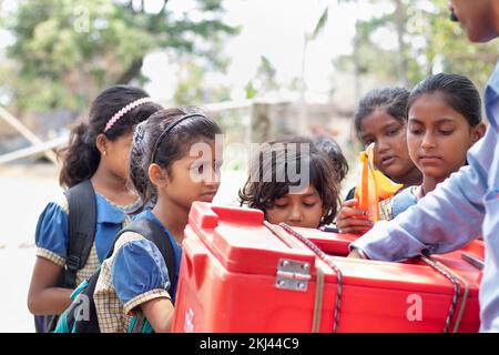 School Children's  Buying  ice lolly with ice-cream seller in village Stock Photo