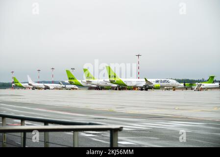 Riga, Latvia - 09 29 2022: View of Riga Airport On Green Planes of AirBaltic. Parking Lot For Aircraft, Against Backdrop Of Cloudy Weather. Stock Photo