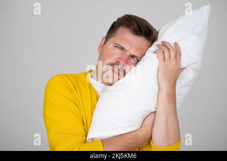 Portrait of Young Caucasian man in bed angry about noise  Stock Photo