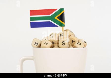 The flag of South Africa sticks out of a cup with cubes on which letters are depicted. Symbol of education. close-up Stock Photo