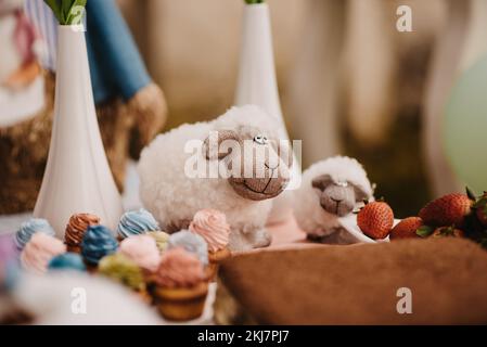 A closeup of fluffy sheep toys on a decorated table against the blurred background Stock Photo
