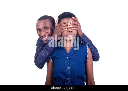 beautiful young couple in love. man covering his wife's eyes with his hands and hiding behind his back smiling. Stock Photo