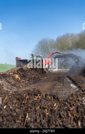 Turning a manure heap over to make compost to spread on farmland, which helps increase the quality of the soil. North Yorkshire, UK. Stock Photo