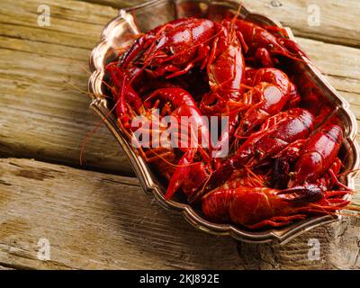 Large bowl with fresh boiled crayfish on a wooden table. Country style. Close-up. View from a narrow angle. Recipe book, food blog. Banner, advertisin Stock Photo