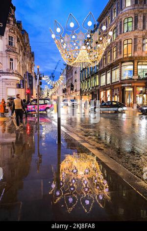 London, UK. 24th Nov, 2022. A large illuminated crown is reflected in the rainy pavement. This year's Christmas Lights in Bond Street, Mayfair's famous shopping street, are royal-themed and feature crowns, tiaras and jewelry, illuminating the street and delighting Christmas shoppers. Credit: Imageplotter/Alamy Live News Stock Photo