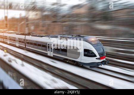 Commuter train traveling at high speed by railways Stock Photo