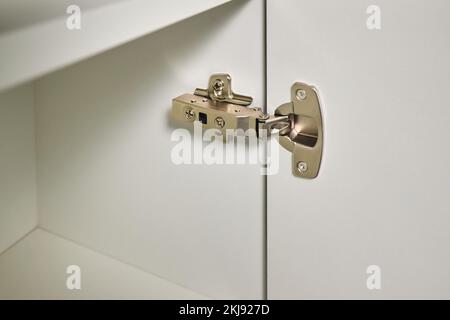 Hinge cabinet of kitchen cupboard door metal furniture isolated on white background, hardware on wood with copyspace. Stock Photo