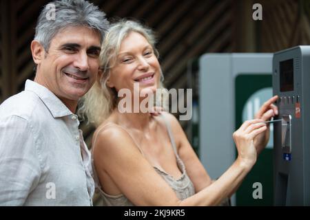 middle aged couple standing at a pay station Stock Photo