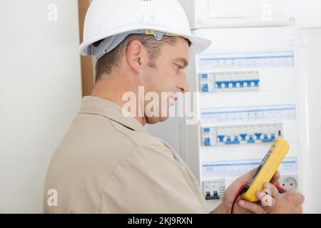 electrician testing circuit breaker cabinet with multimeter Stock Photo