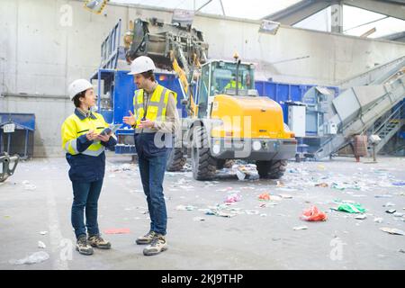 two workers talking in a recycling center Stock Photo