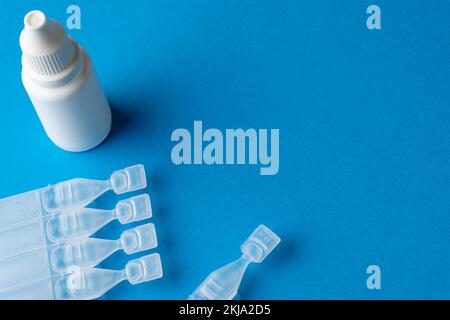 Composition of saline solution caplets and dropper bottle on blue ...