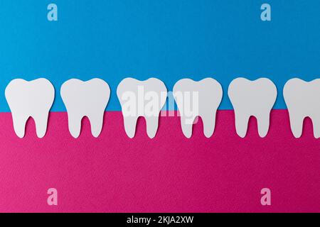 Composition of row of white teeth in pink gum on blue background, with copy space Stock Photo