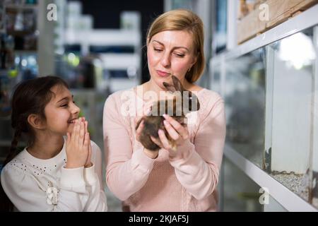 Mother with her daughter holding rabbit together at pet store Stock Photo