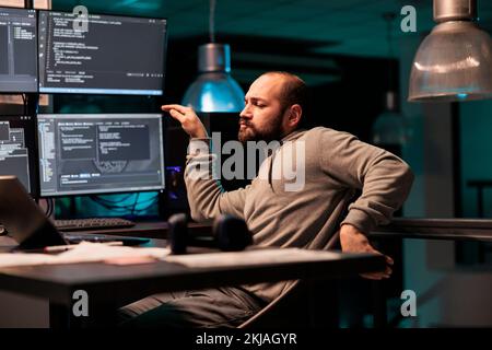 Male app developer feeling happy and dancing in office, celebrating programming and source code. Cheerful software engineer enjoying achievement, compiling database server at night. Stock Photo