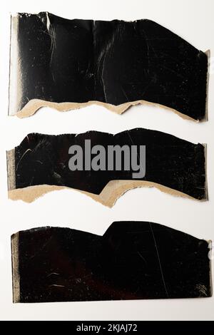 Ripped up pieces of black cardboard with copy space on white background Stock Photo