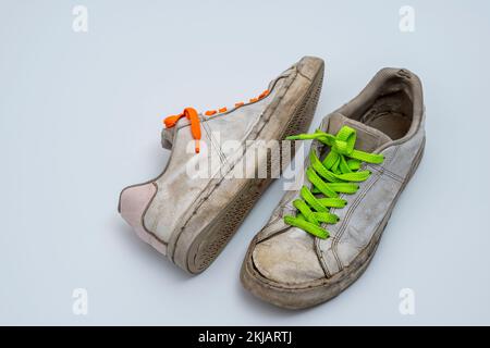 worn old torn white sneakers with colored laces on a white background Stock Photo