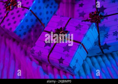 Gifts Christmas in neon light. Wrapped in wrapping paper and bows boxes. New Year 2023. Merry Christmas. Shopping. Stock Photo