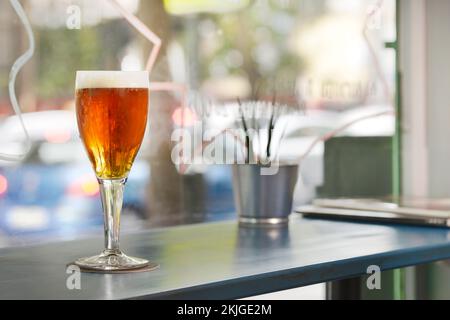 A glass of freshly drafted beer on a tall wooden table Stock Photo