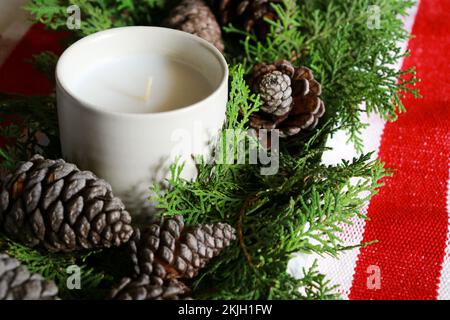 christmas composition with a candle, pine cones and green needles with red table runner  Stock Photo