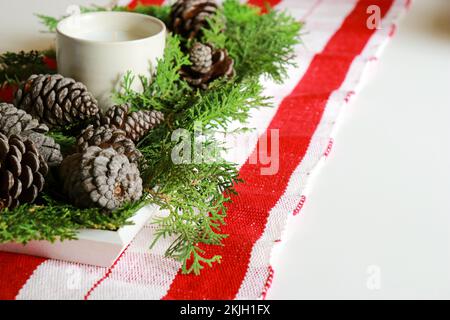 christmas composition with a candle, pine cones and green needles with red table runner  Stock Photo