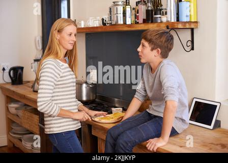 Mom always makes the best sandwiches. A cropped shot of a mother making her young son a sandwich in the kitchen. Stock Photo