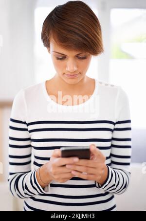 Focused on finding the perfect reply. an attractive young woman focused on texting. Stock Photo