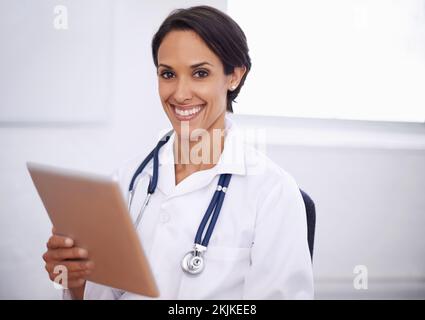Keeping up-to-date is easy. Portrait of a happy young doctor using a digital tablet. Stock Photo